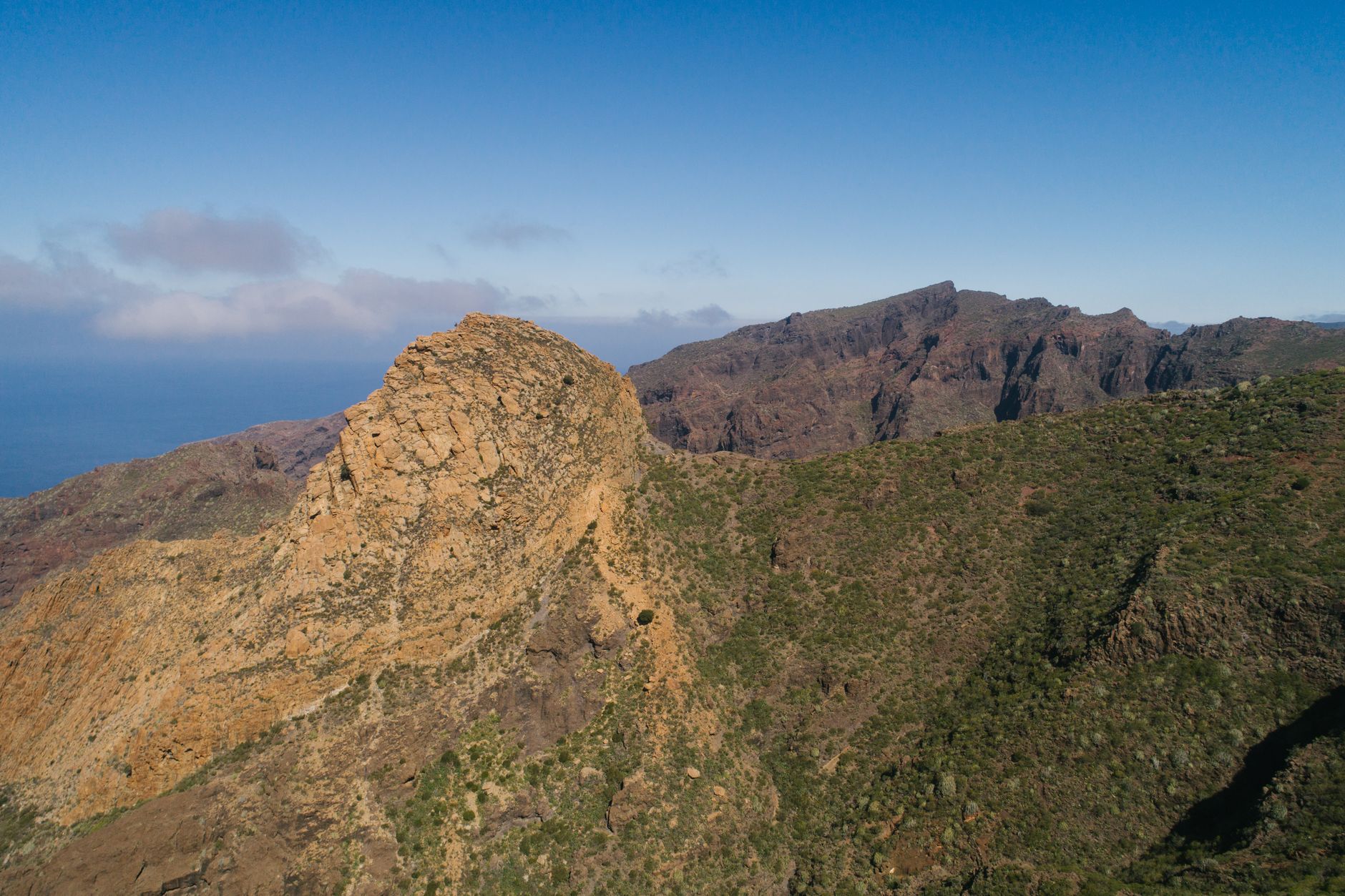 Stunning aerial shot of a rocky mountain terrain under a clear blue sky in Tenerife, Spain.