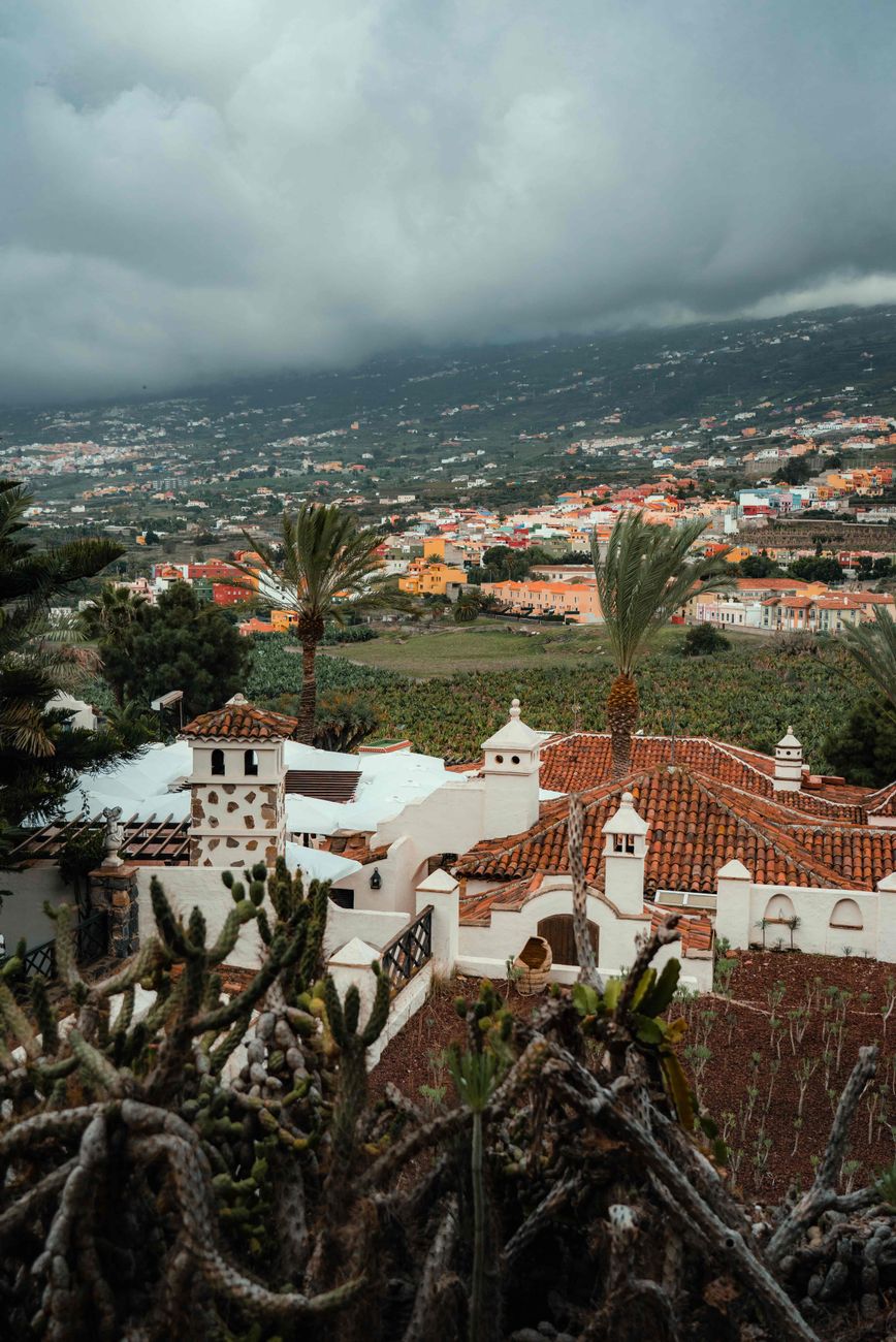 Dramatic sky over Puerto de la Cruz town with palm trees and colorful architecture.